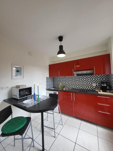 une cuisine avec des armoires rouges et une table et des chaises dans l'établissement Les couleurs de Schiltigheim, à Schiltigheim