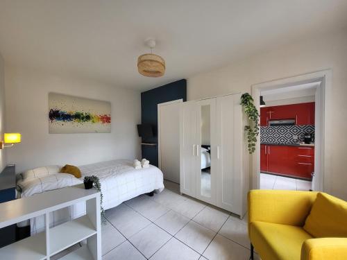 Cet appartement comprend une chambre avec un lit et une cuisine avec des placards rouges. dans l'établissement Les couleurs de Schiltigheim, à Schiltigheim