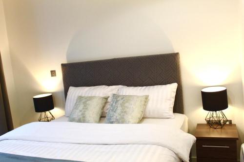 a bedroom with a large white bed with two lamps at Apartment in MediaCity in Manchester