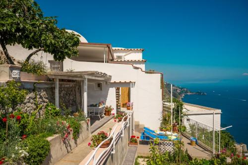 una casa blanca en la ladera de una colina con flores en Blue Moon House Praiano, en Praiano