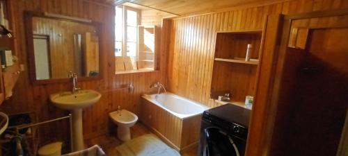 La salle de bains est pourvue d'un lavabo, d'une baignoire et de toilettes. dans l'établissement Maison Authentique en Ubaye, à Jausiers