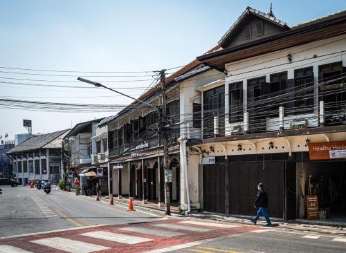 a person walking down a street next to a building at Historic Villa in Thapae in Chiang Mai
