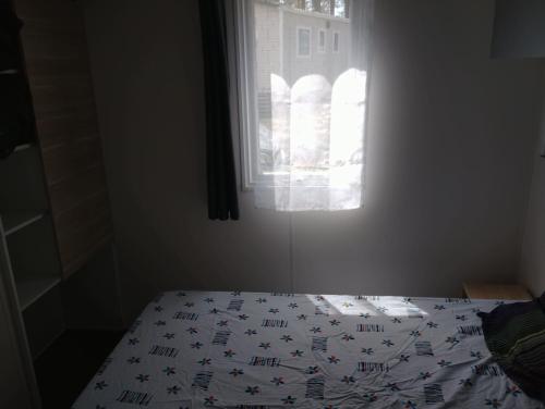 un lit dans une chambre avec une fenêtre dans l'établissement MH 285 O'HARA 3 chambres et 1 salle de bain dans camping 4 étoiles, à Saint-Julien-en-Born