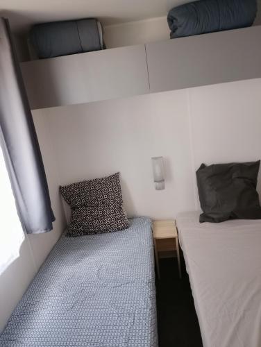 une petite chambre avec deux lits et une fenêtre dans l'établissement MH 285 O'HARA 3 chambres et 1 salle de bain dans camping 4 étoiles, à Saint-Julien-en-Born