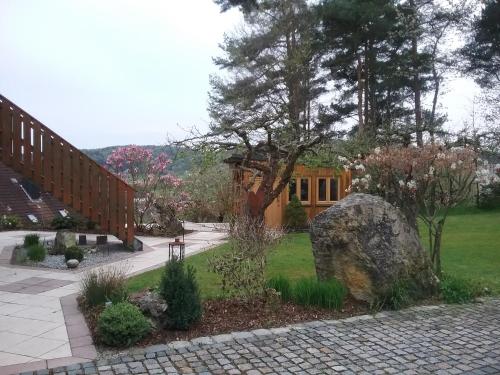 a garden with a large rock and a house at Pension am Wald in Gößweinstein