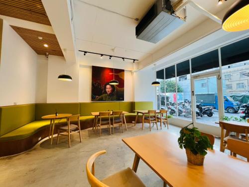 a restaurant with tables and chairs and a green bench at 有某行旅 yóu mǒu hostel in Tainan
