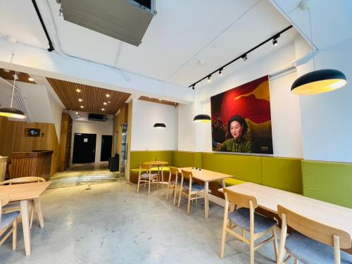a restaurant with wooden tables and green walls at 有某行旅 yóu mǒu hostel in Tainan