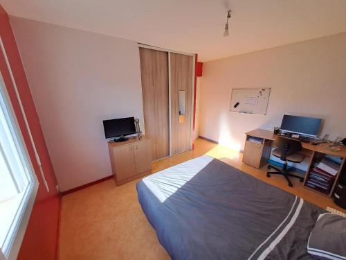 une chambre avec un lit et un bureau avec un ordinateur dans l'établissement Chambre chez nous, à La Haie-Fouassière