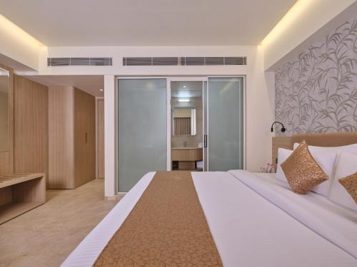 a bedroom with a large white bed and a bathroom at Biznotel By Pride Motera in Ahmedabad