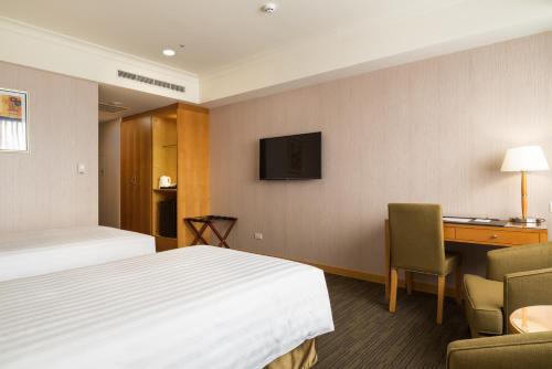 a hotel room with a bed and a desk and a television at Fushin Hotel Taipei in Xizhi