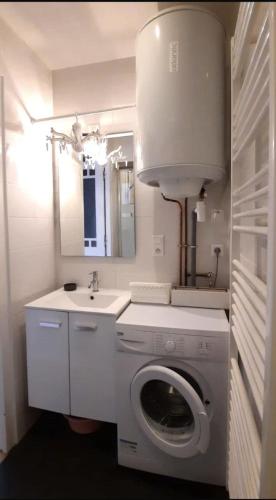 une salle de bain blanche avec une machine à laver et un lavabo dans l'établissement Appartement 2 pièces 42m2 - Puces de Saint-Ouen, à Saint-Ouen