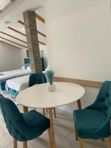 a dining room with a white table and blue chairs at Yugoslavija Lux 3 in Aleksandrovac