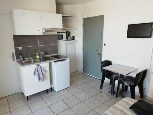 une cuisine avec un évier et une table avec des chaises dans l'établissement Studio résidence la Sardane vue mer, au Barcarès