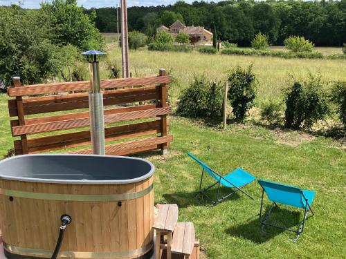 - un bain à remous et deux chaises dans la cour dans l'établissement Cabane luxe & spa extérieur Les Magnolias, à Barjou