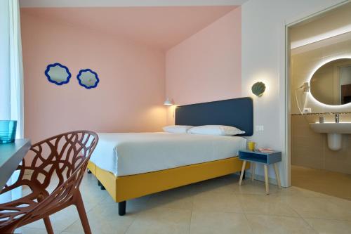 a bedroom with a bed and a chair and a sink at La Vista Postcard Hotel in Lazise