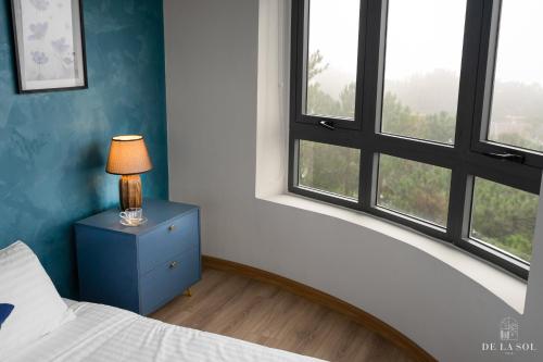 a bedroom with a bed and a lamp on a dresser at De La Sol Villa Dalat in Da Lat