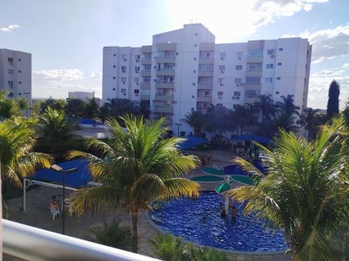 a view of a pool with palm trees and buildings at Confortável Apto de 2 Quartos - Lagoa Quente in Caldas Novas
