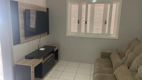 a living room with a couch and a tv at FIKA Residence in Dois Irmãos
