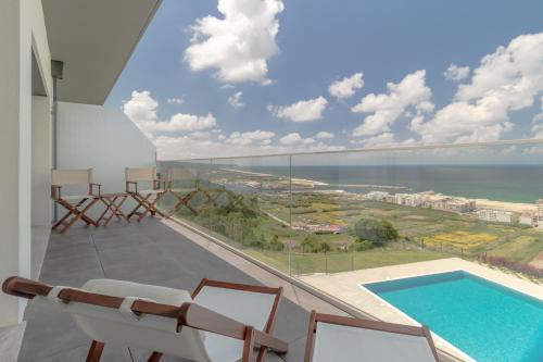 a balcony with a view of a swimming pool and chairs at Caminho Real Guest Apartment I in Nazaré
