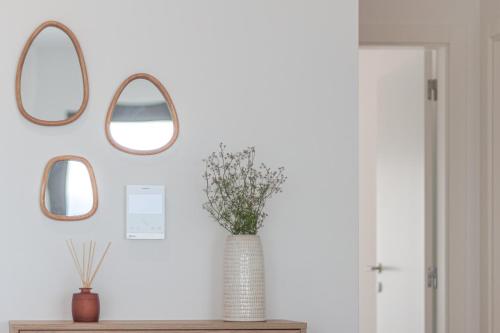 a vase on a table with three mirrors on a wall at Caminho Real Guest Apartment I in Nazaré