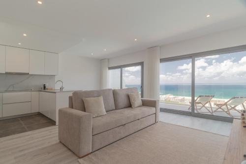 a living room with a couch and a view of the ocean at Caminho Real Guest Apartment I in Nazaré