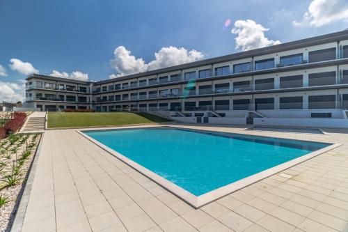 a building with a swimming pool in front of a building at Caminho Real Guest Apartment I in Nazaré