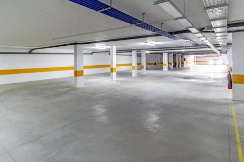 an empty parking garage with yellow and white columns at Caminho Real Guest Apartment I in Nazaré