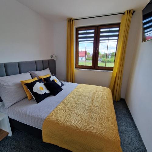 a bedroom with a bed with yellow curtains and a window at Pluma in Grzybowo