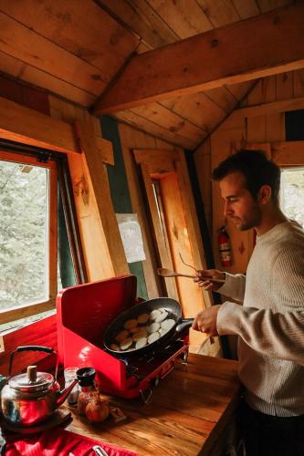 a man is cooking food on a grill at Les Toits Du Monde in Nominingue