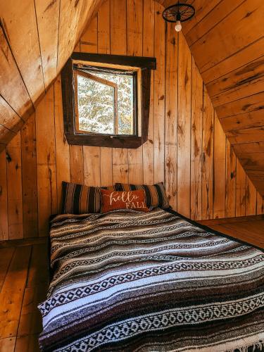 a bed in a log cabin with a window at Les Toits Du Monde in Nominingue