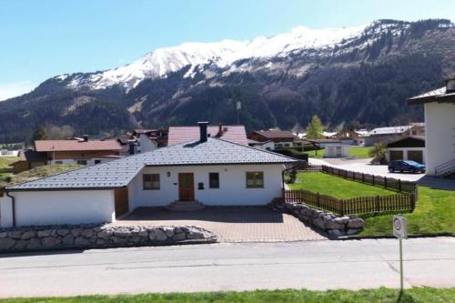 ein weißes Haus mit einem Berg im Hintergrund in der Unterkunft Billes gemütliches Gästezimmer Zugspitz Arena in Bichlbach