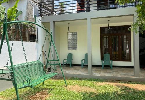 a swing in front of a house with two chairs at Conch Homestay in Homagama
