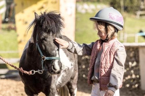 a woman is petting a black horse at Alpin Family Resort Seetal in Kaltenbach