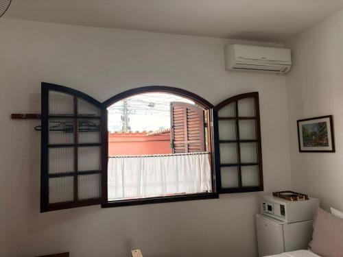 an arched window in a room with a refrigerator at Pousada Cantinho de Minas Da Tânia in Cabo Frio