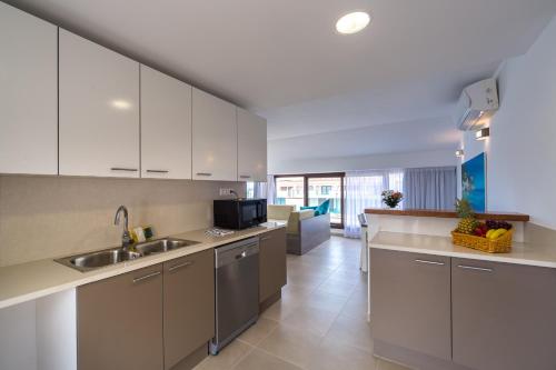 a kitchen with white cabinets and a sink at Aparthotel Caprice Skyline in Ciutadella
