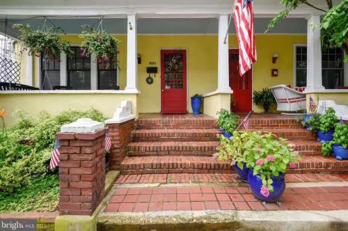 a yellow house with a red door and stairs at Historic Row Home 1 Block from Gate 1 at USNA in Annapolis