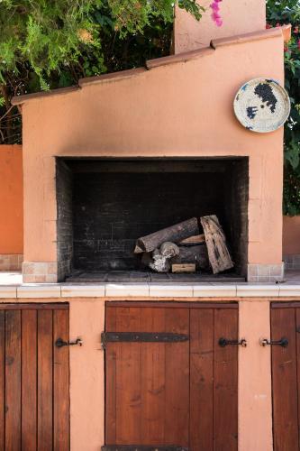 a fireplace with a piece of wood on top of it at The Peacock house in Flumini di Quartu