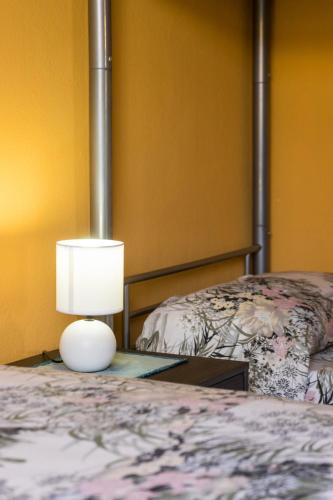 a lamp sitting on a table next to a bed at The Peacock house in Flumini di Quartu