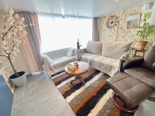 a living room with a couch and a table at Maison des Vignes avec ménage, draps et serviettes inclus in Tabanac