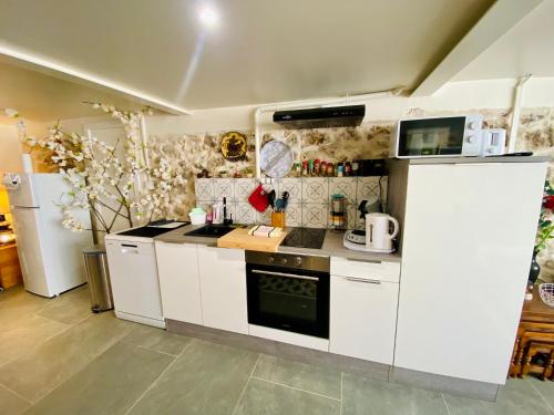 a kitchen with white cabinets and a stove top oven at Maison des Vignes avec ménage, draps et serviettes inclus in Tabanac