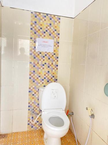 a bathroom with a toilet and a tile wall at Villa Pondok Ima in Tlekung