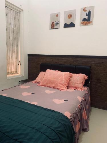 a bedroom with a bed with pink comforter at Villa Pondok Ima in Tlekung