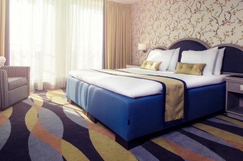 a bedroom with a large blue bed with a chair at Carlton Oasis Hotel in Spijkenisse