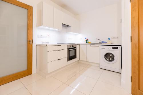 a kitchen with white cabinets and a washer and dryer at 'Amalfi' Coast Road, Oranmore in Galway