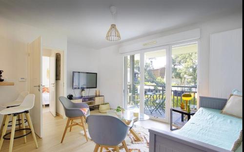 un salon avec un lit, une table et des chaises dans l'établissement Appartement Lumineux et Calme, à Capbreton