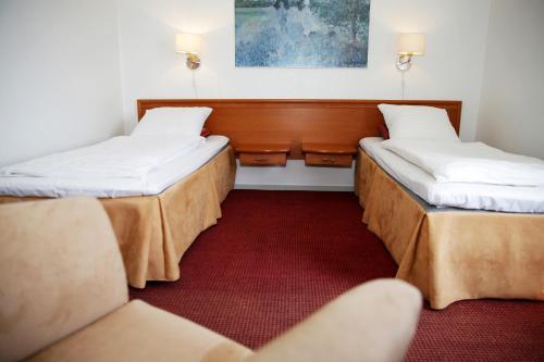 Habitación con 2 camas y alfombra roja. en Motel Højmølle Kro, en Eskilstrup
