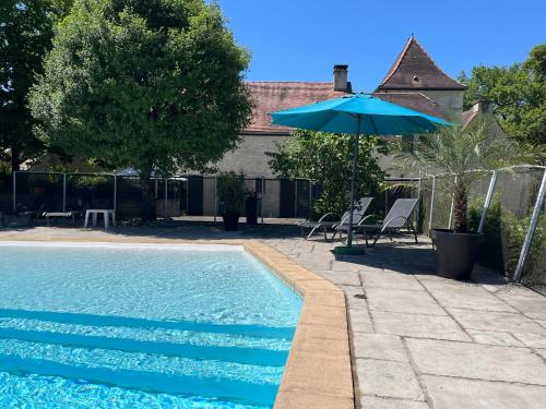 - une piscine avec un parasol bleu et des chaises dans l'établissement Domaine Rossignol Tournesol, à Gourdon