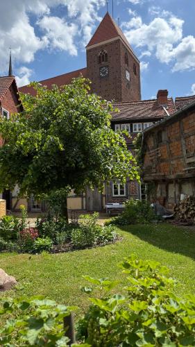 a building with a clock tower and a tree in a yard at Ferienhaus St. Johannis in Werben