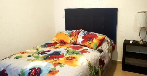 a bed with a colorful comforter with a pillow on it at Increible Apartment with beach Monterrey/Apodaca in Monterrey