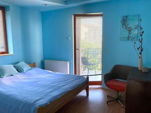 a bedroom with blue walls and a bed and a chair at Artists Inn, large 2 bed duplex apartment, parking in Železnička Stanica Zemunsko Polje